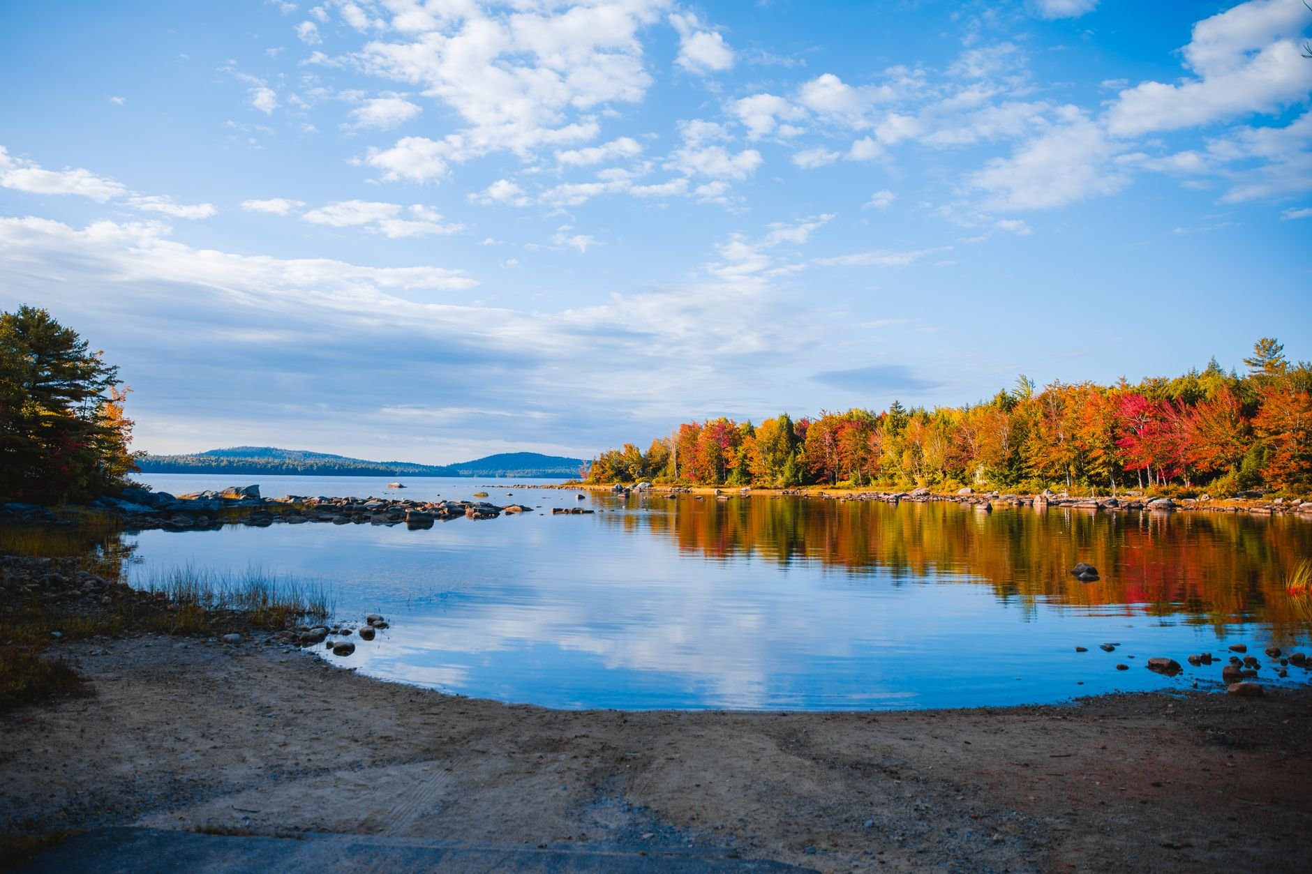 Capture of autumn foliage reflecting in serene water at Steuben Lake, Maine, showcasing vibrant fall colors.